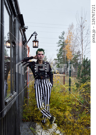 Stylish Character in Striped Pants Posing Outdoors Against a Beautiful Scenic Background Stylish Character in Striped Pants Posing Outdoors Against a Beautiful Scenic Background 126767221