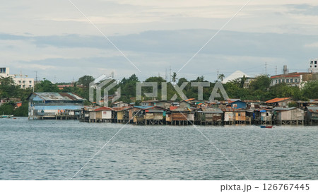 Tropical slum homes on stilts near ocean backed by modern buildings in Lapu-Lapu City  126767445