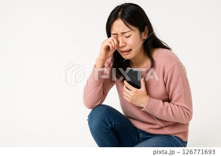 白背景でスマホ破損に涙する女性の横長写真素材 白背景でスマホ破損に涙する女性の横長写真素材 126771693
