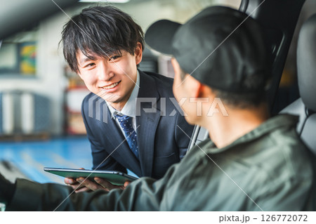 車内にいる作業着姿の作業員に指示をするスーツ姿の若いアジア人ビジネスマン 126772072