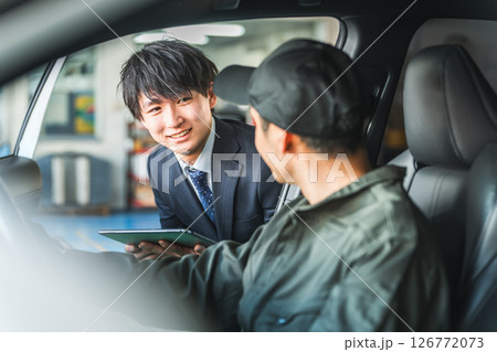 車内にいる作業着姿の作業員に指示をするスーツ姿の若いアジア人ビジネスマン 126772073