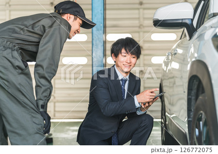 車の傷・凹みを確認する整備士の男性とスーツ姿のセールスマン 126772075