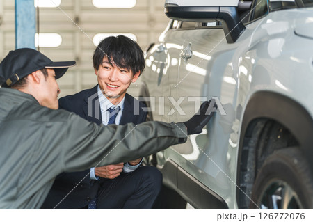 車の傷・凹みを確認する整備士の男性とスーツ姿のセールスマン 126772076