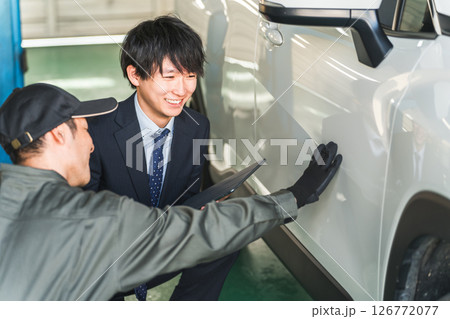 車の傷・凹みを確認する整備士の男性とスーツ姿のセールスマン 126772077