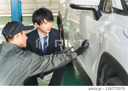 車の傷・凹みを確認する整備士の男性とスーツ姿のセールスマン 126772078