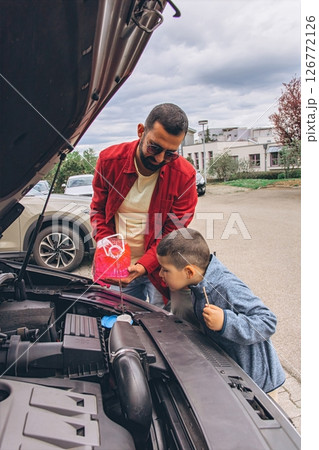 Father and sons repairing car together with the hood open. A heartfelt moment of bonding, fatherhood, parenting, teamwork, and learning. Celebrating Father Day through shared hands-on experience. Father and sons repairing car together with the hood open. A heartfelt moment of bonding, fatherhood, parenting, teamwork, and learning. Celebrating Father Day through shared hands-on experience. 126772126