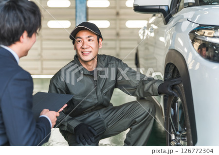 自動車の前で会話する自動車整備士の男性とスーツ姿のフロントマン・営業マン 126772304