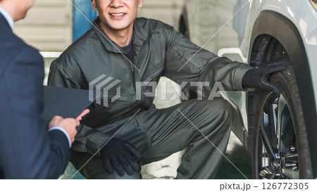 自動車の前で会話する自動車整備士の男性とスーツ姿のフロントマン・営業マン 126772305
