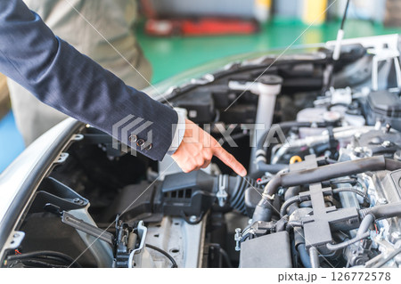 自動車のエンジンルームを指差すスーツ姿の男性ビジネスマンの手元 126772578