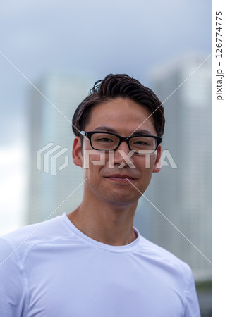 黒縁メガネをかけた、白いTシャツ姿の笑顔の男性 126774775
