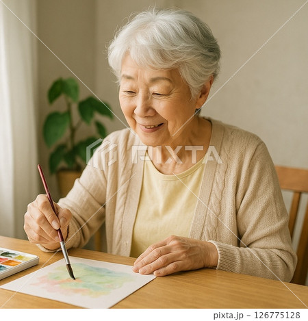 窓辺で水彩画制作に集中するシニア女性の創作写真 126775128