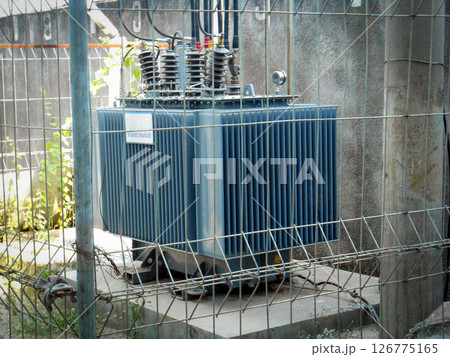 High Voltage Transformer Enclosed Behind Metal Fencing in an Industrial Setting High Voltage Transformer Enclosed Behind Metal Fencing in an Industrial Setting 126775165