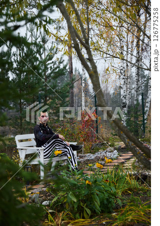 A man dressed in stylish striped pants is relaxing peacefully in a beautiful autumn garden 126775258