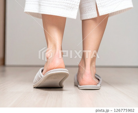 くつろぎの足元：フローリングを優しく歩くスリッパ姿の女性 - 自宅でのリラックスタイムと快適な室内 126775902
