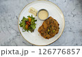 Crispy Breaded Cutlet with Fresh Salad and Citrus Dressing on a Marble Tabletop 126776857