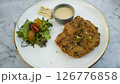 Crispy Breaded Cutlet with Fresh Salad and Citrus Dressing on a Marble Tabletop 126776858