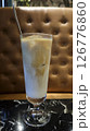 Refreshing iced latte in a tall glass served on a black marble table with a brown tufted leather background in a cozy cafe setting 126776860