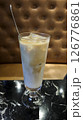 Refreshing iced latte in a tall glass served on a black marble table with a brown tufted leather background in a cozy cafe setting 126776861