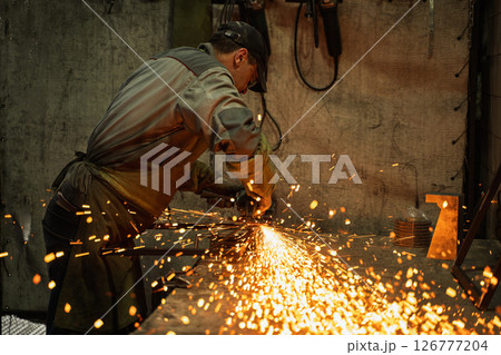 Industrial Metalworker Using Angle Grinder in Workshop with Flying Sparks Industrial Metalworker Using Angle Grinder in Workshop with Flying Sparks 126777204