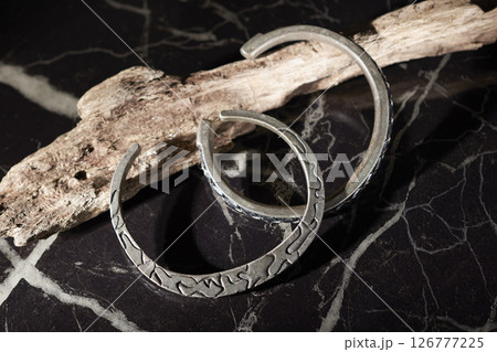 黒い大理石の上に置いてある流木と二つのシルバーのバングル 126777225