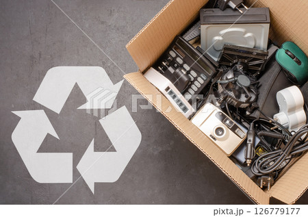 Old electronic devices in a cardboard box. The concept of recycling used gadgets. Black background 126779177