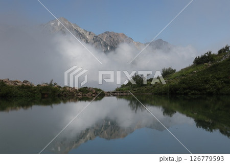 雲の中から現れる白馬三山とそれを写し出す八方池 126779593