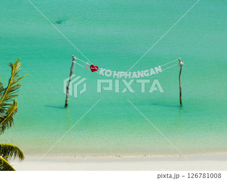 The Koh Phangan sign displayed over turquoise waters close to a white sandy shore under a sunny sky. Ko Pha Ngan, Thailand. 126781008
