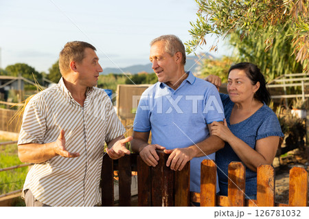 Man talking with mature couple neighbours at garden 126781032