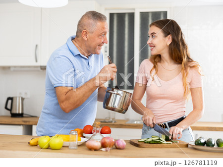Happy father spending time with adult daughter - preparing lunch together in kitchen 126781119