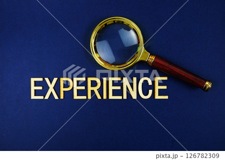 Experience alphabet letters with magnifying glass on navy blue background 126782309