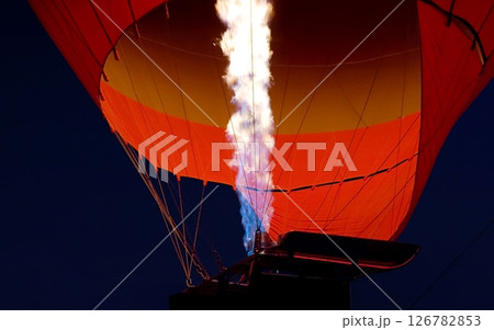 Strong flames inflate a bright red hot air balloon. A flight in Cappadocia. Turkey travel. Flames of a large fire and a balloon glowing in the dark. Tourist tour, Turkish culture, majestic journey 126782853
