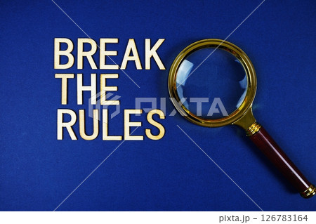 Break The Rules alphabet letters with magnifying glass on navy blue background 126783164
