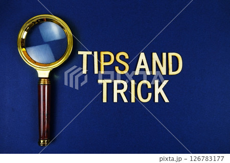 Tips and Trick alphabet letters with magnifying glass on navy blue background 126783177