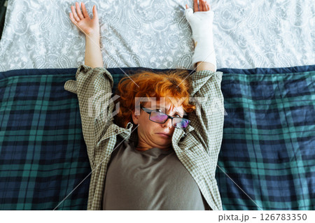 Teen girl with broken arm, wearing glasses, red hair, in bedroom 126783350