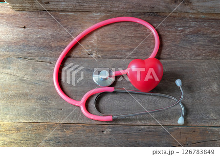 Red heart and a pink stethoscope on wood table. Red heart and a pink stethoscope on wood table. 126783849