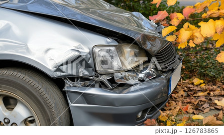 Damaged silver car front with autumn leaves after collision 126783865