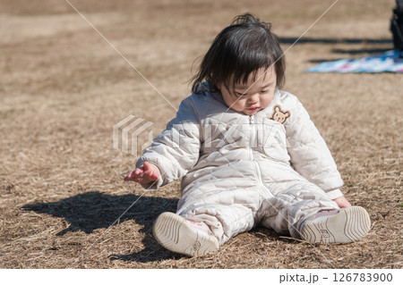 【相模原市立麻溝公園の芝生広場で遊ぶ1歳児　座る】 126783900