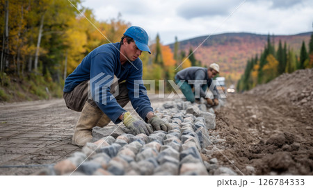 Road work team reinforcing an embankment in fall landscape 126784333