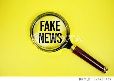 Fake News text with magnifying on yellow background 126784475