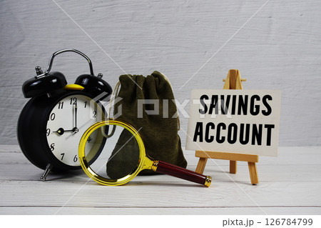 Savings Account text with alarm clock and magnifying glass on wooden background 126784799