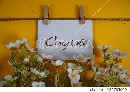 Congrats text on paper card with flower blooming decoration on yellow background Congrats text on paper card with flower blooming decoration on yellow background 126785000