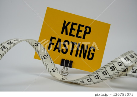 Keep Fasting text with alarm clock on white background Keep Fasting text with alarm clock on white background 126785073