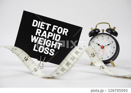 Diet For Rapid Weight Loss text with alarm clock and measuring tape on white background 126785093