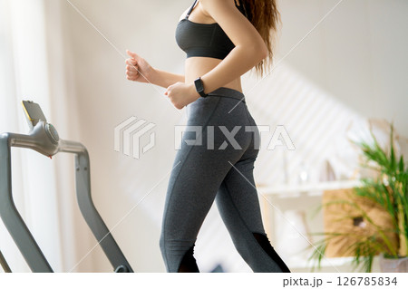 Young woman running on a treadmill indoors Young woman running on a treadmill indoors 126785834