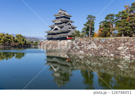 Historic Matsumoto Castle with its striking reflection in the moat, framed by Japanese pines Historic Matsumoto Castle with its striking reflection in the moat, framed by Japanese pines 126786051