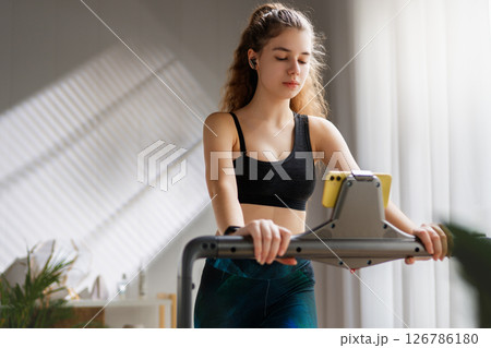 Young woman running on a treadmill indoors Young woman running on a treadmill indoors 126786180