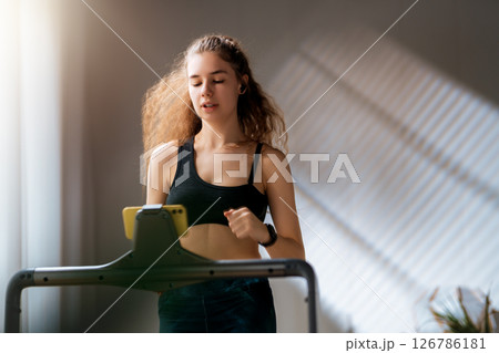 Young woman running on a treadmill indoors 126786181