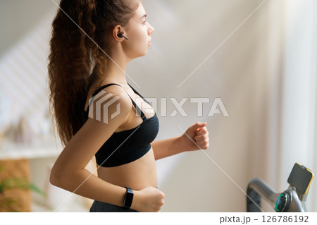 Young woman running on a treadmill indoors Young woman running on a treadmill indoors 126786192