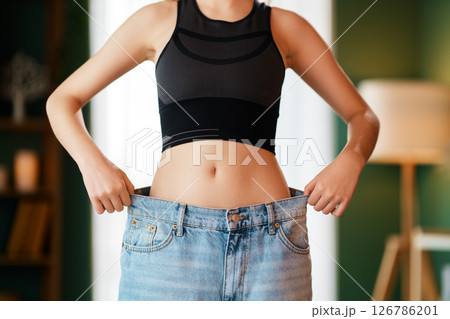 A young woman is trying on big jeans 126786201
