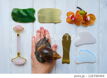 Spa concept gua sha massage body and face care and snails achatina on hand, flat lay. High quality photo 126786469
